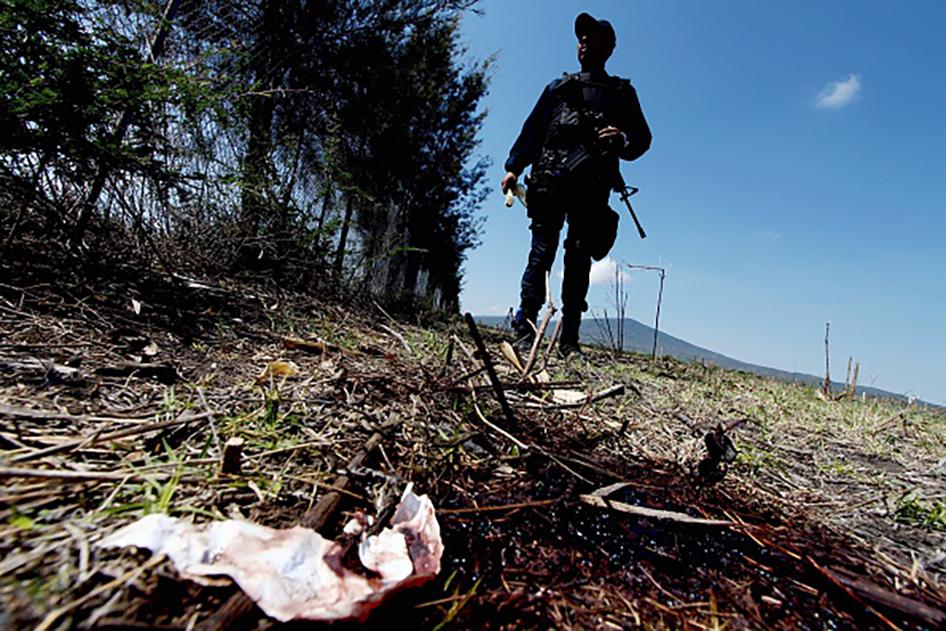 Un miembro de la policía estatal parado junto a una mancha de sangre durante una búsqueda de pruebas el 23 de mayo 2015, en un rancho ubicado en la carretera Jalisco-Michoacán en la región de Tanhuatose, Michoacán, México; donde 42 personas murieron a manos de las fuerzas de seguridad mexicanas. © 2015 Getty Images